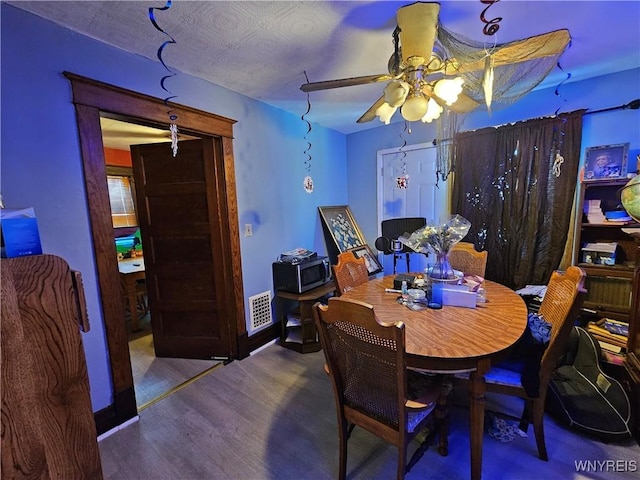 dining space featuring baseboards, visible vents, a ceiling fan, and wood finished floors