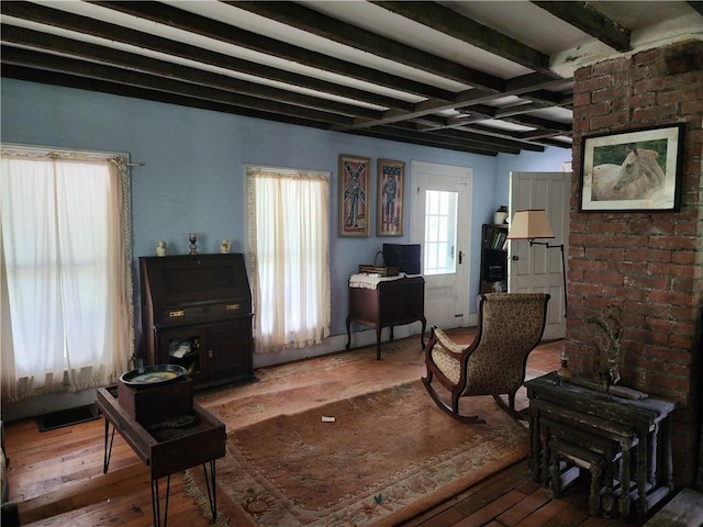 living area with wood-type flooring and beam ceiling