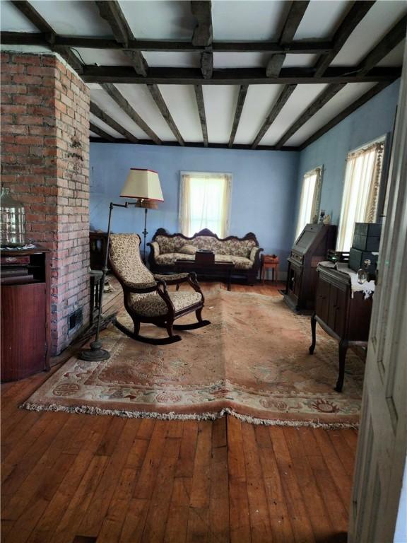 living room with plenty of natural light, hardwood / wood-style floors, and beam ceiling