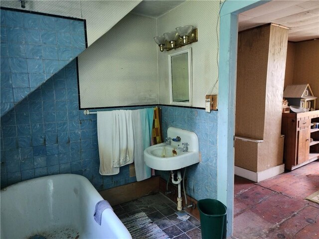 bathroom featuring a bathing tub, sink, and tile walls