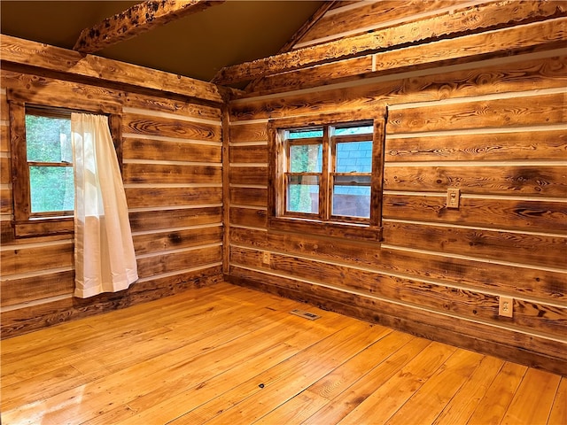 empty room with hardwood / wood-style flooring, a healthy amount of sunlight, and wooden walls