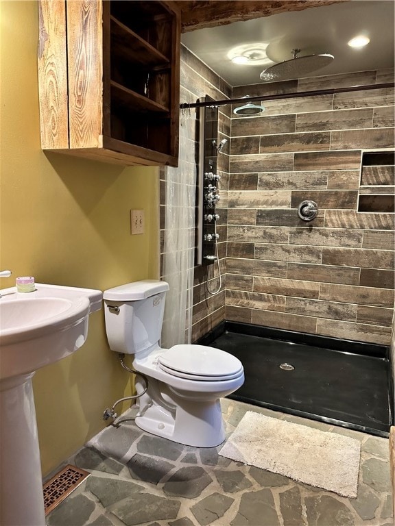 bathroom featuring tiled shower, tile patterned flooring, and toilet