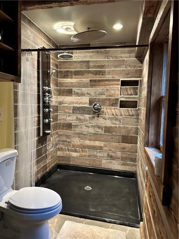 bathroom featuring tiled shower, tile patterned flooring, and toilet