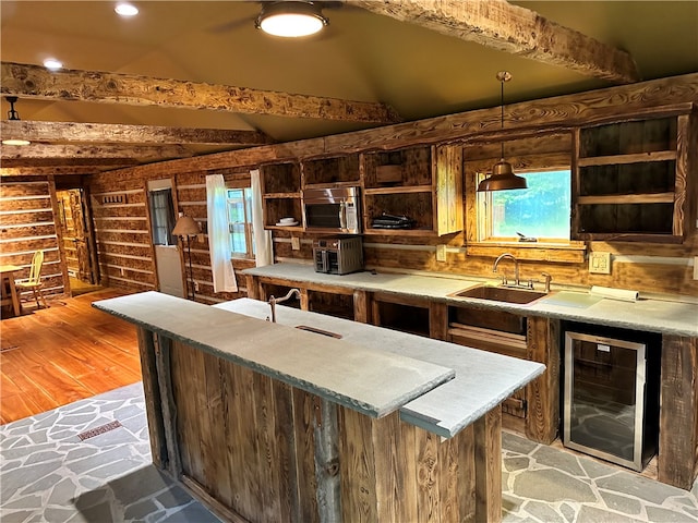 kitchen featuring decorative light fixtures, vaulted ceiling with beams, beverage cooler, sink, and light hardwood / wood-style flooring