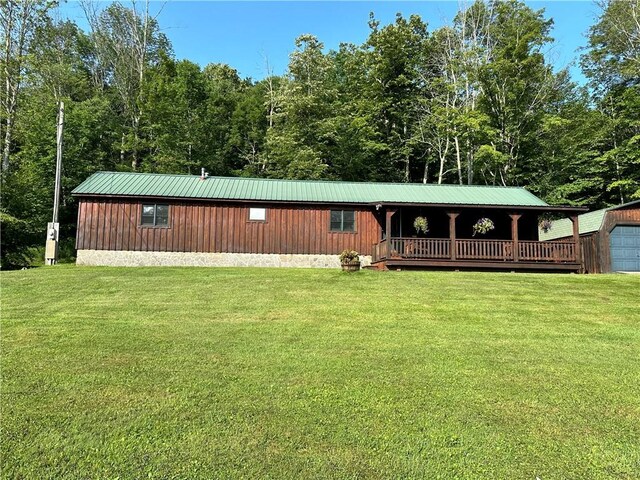 rear view of house with a garage, a lawn, and an outbuilding