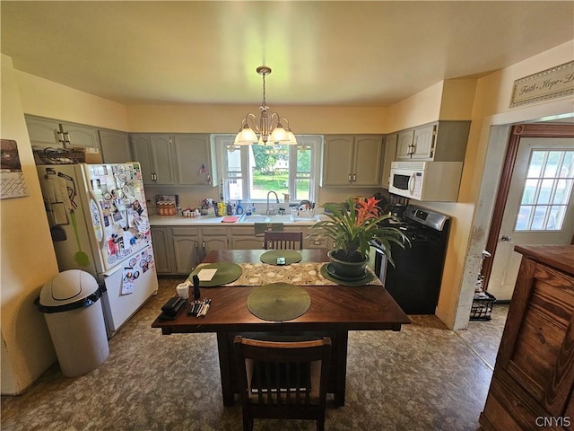 kitchen featuring pendant lighting, sink, white appliances, and a notable chandelier