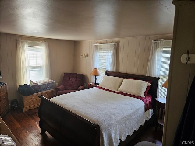 bedroom with dark wood-type flooring and wood walls