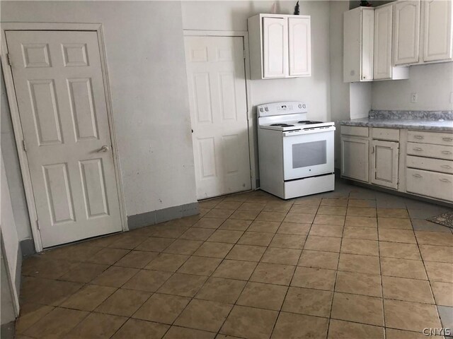 kitchen featuring tile patterned flooring, electric range, and white cabinetry