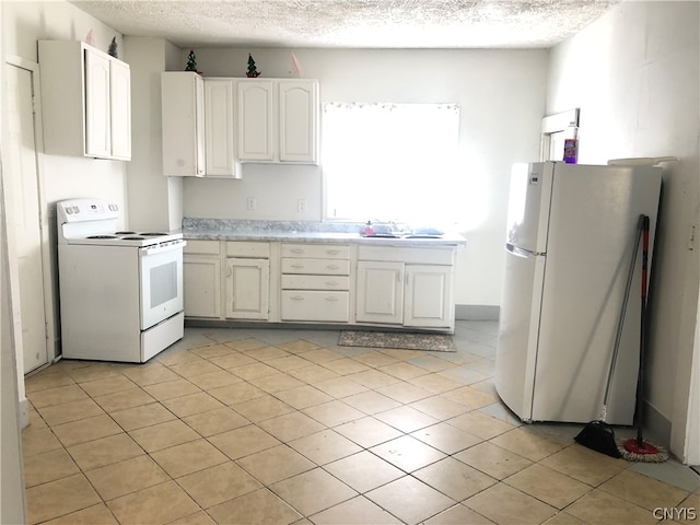 kitchen with light tile patterned floors, a textured ceiling, white cabinets, and white appliances