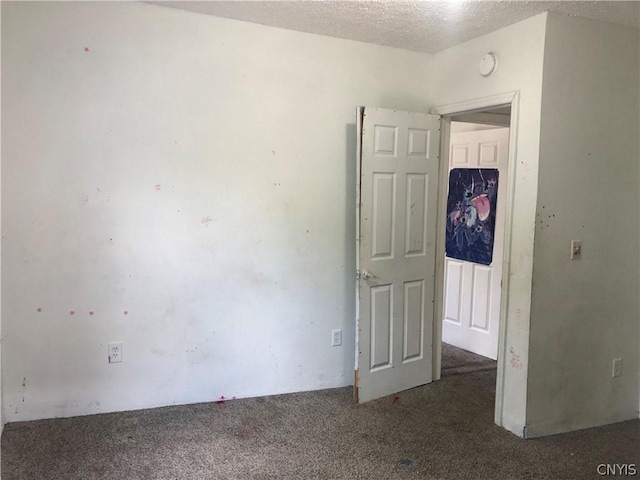 carpeted empty room featuring a textured ceiling