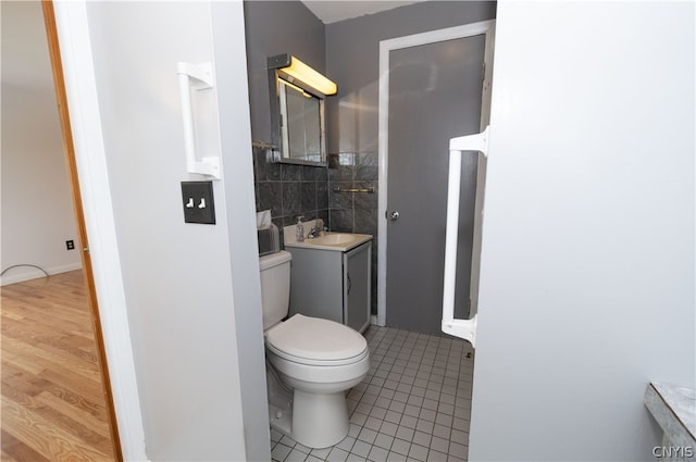 bathroom featuring vanity, tile patterned flooring, toilet, and tile walls