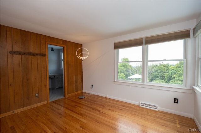 unfurnished room featuring wooden walls and light hardwood / wood-style flooring