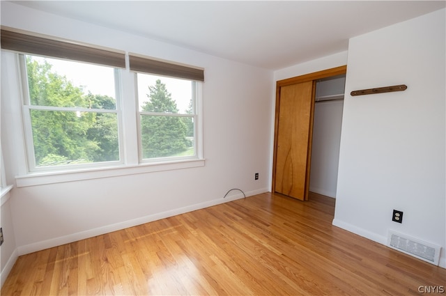 unfurnished bedroom featuring light hardwood / wood-style flooring and a closet