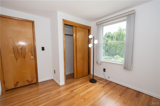 unfurnished bedroom featuring multiple windows, light hardwood / wood-style flooring, and a closet