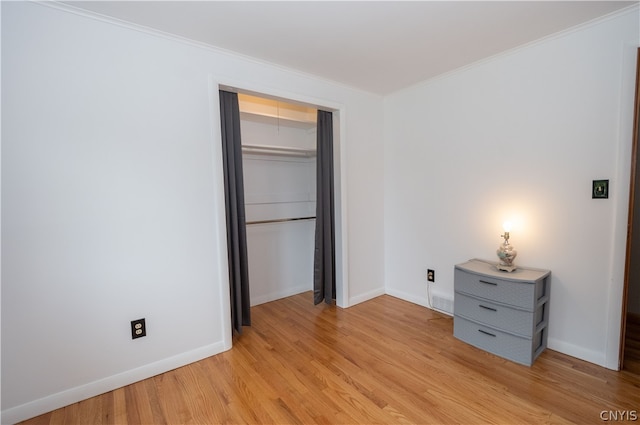 unfurnished bedroom with light hardwood / wood-style flooring, a closet, and ornamental molding