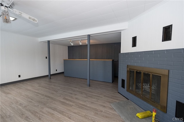 unfurnished living room featuring ceiling fan, a fireplace, hardwood / wood-style flooring, and rail lighting