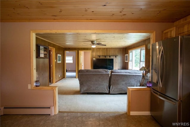 unfurnished living room with ceiling fan, baseboard heating, wooden ceiling, light colored carpet, and wood walls