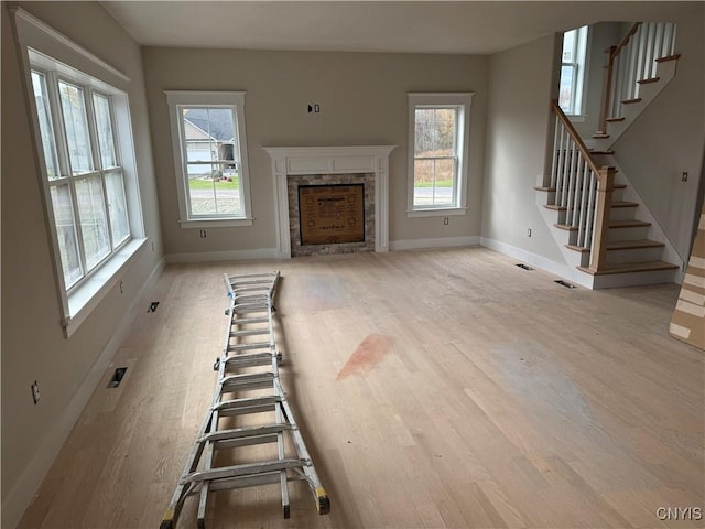 unfurnished living room with light hardwood / wood-style floors and a stone fireplace