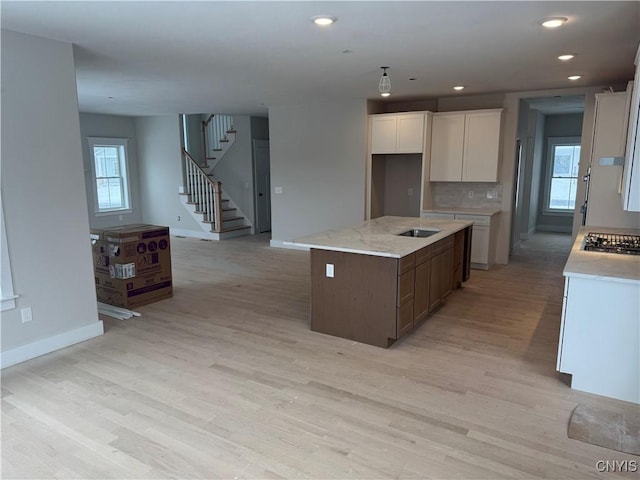 kitchen with white cabinetry, a center island, plenty of natural light, and light hardwood / wood-style flooring