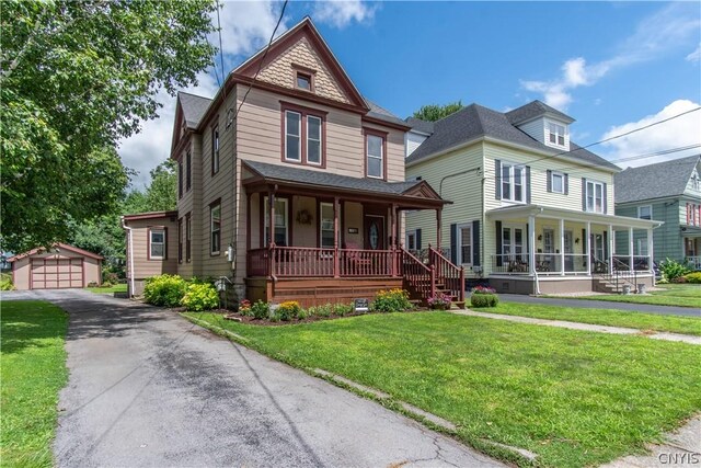 victorian home with covered porch, an outbuilding, a garage, and a front yard