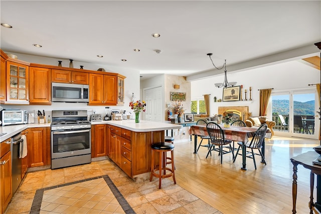 kitchen featuring pendant lighting, a healthy amount of sunlight, appliances with stainless steel finishes, and a breakfast bar area