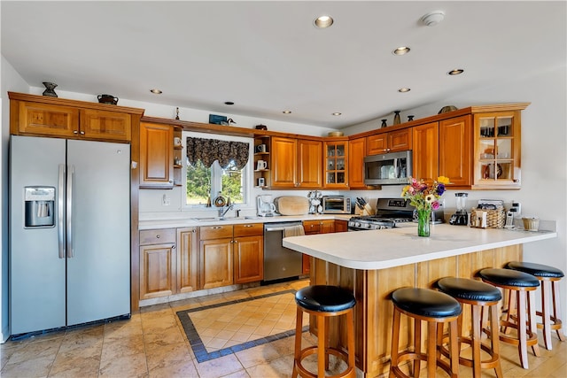 kitchen featuring a breakfast bar, stainless steel appliances, kitchen peninsula, and sink