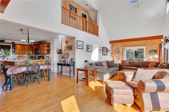 living room featuring a high ceiling, a chandelier, and light hardwood / wood-style flooring