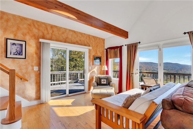 interior space with high vaulted ceiling, access to outside, a mountain view, beamed ceiling, and light hardwood / wood-style floors