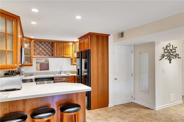 kitchen featuring light tile patterned flooring, sink, a kitchen breakfast bar, kitchen peninsula, and stainless steel appliances