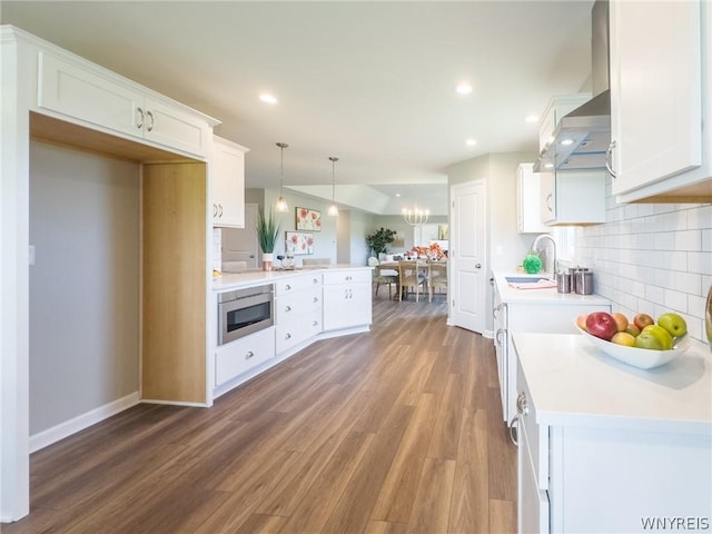 kitchen featuring sink, hanging light fixtures, stainless steel microwave, decorative backsplash, and white cabinets