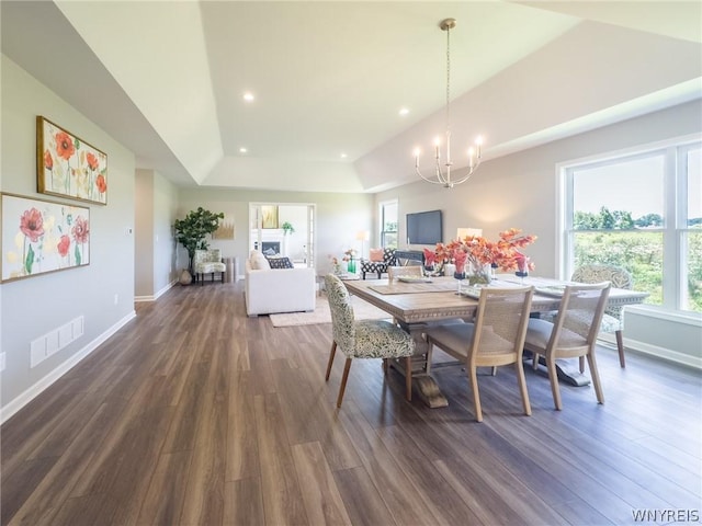 dining space with an inviting chandelier, dark hardwood / wood-style flooring, and a raised ceiling