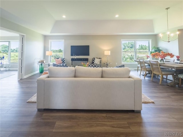 living room with dark hardwood / wood-style floors, a chandelier, and a tray ceiling