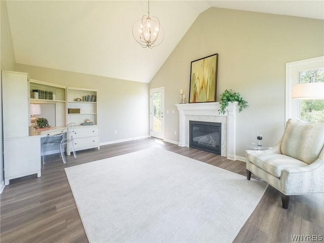 living room featuring a premium fireplace, dark wood-type flooring, an inviting chandelier, and high vaulted ceiling