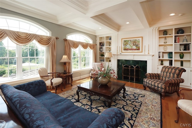 living room with coffered ceiling, a premium fireplace, wood-type flooring, and ornamental molding