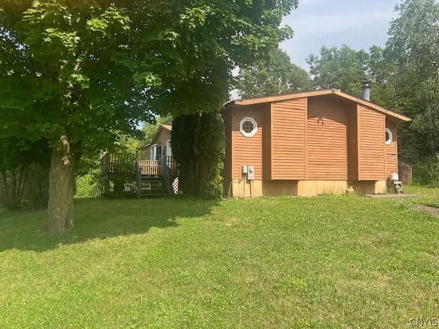 view of side of home with a wooden deck and a lawn