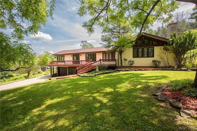 view of front of house with a front yard, concrete driveway, a wooden deck, and stairs