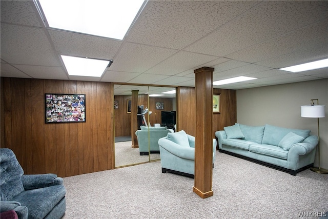 living room with a paneled ceiling, carpet floors, and wooden walls