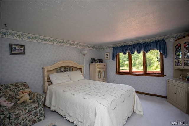 bedroom with light carpet, wallpapered walls, baseboards, and a textured ceiling