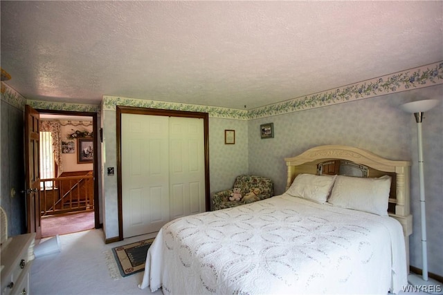 bedroom featuring wallpapered walls, carpet, a closet, and a textured ceiling