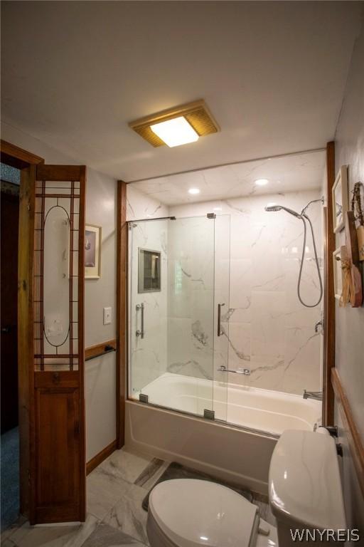 bathroom featuring enclosed tub / shower combo, marble finish floor, toilet, and baseboards