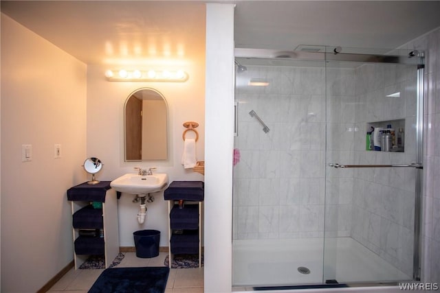 bathroom featuring baseboards, a stall shower, a sink, and tile patterned floors