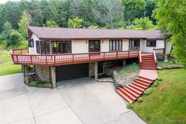 ranch-style home featuring a sunroom, a garage, a deck, and a front lawn