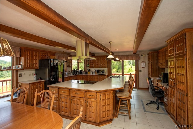 kitchen with beam ceiling, hanging light fixtures, a wealth of natural light, and island range hood