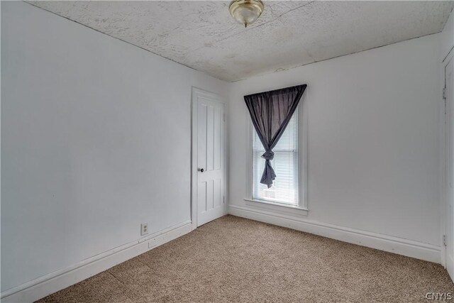 unfurnished room with light colored carpet and a textured ceiling