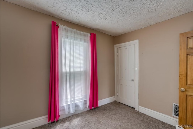 carpeted empty room with a textured ceiling