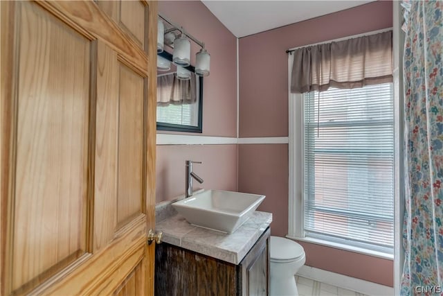 bathroom featuring toilet, vanity, and plenty of natural light