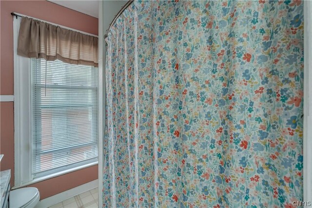 bathroom with a healthy amount of sunlight, tile patterned floors, and toilet