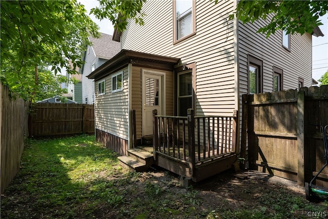 back of house with a wooden deck and a lawn