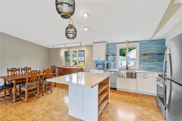 kitchen with appliances with stainless steel finishes, light parquet flooring, a healthy amount of sunlight, and white cabinets