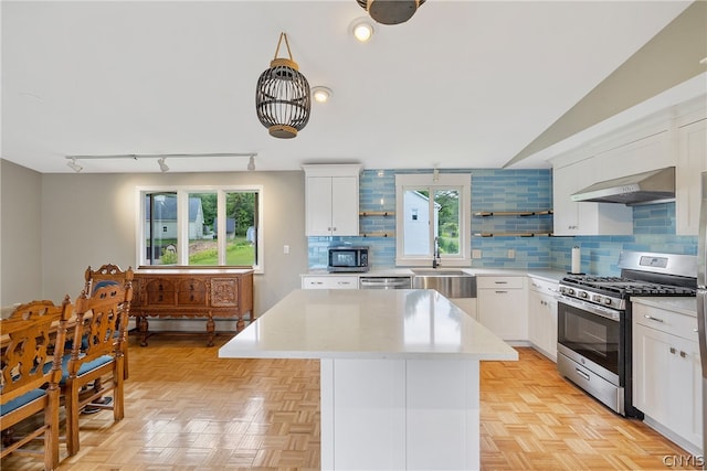 kitchen with appliances with stainless steel finishes, a center island, wall chimney exhaust hood, and light parquet floors